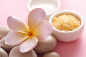 bowl of aromatherapy bath salt, pebbles and frangipani flowers